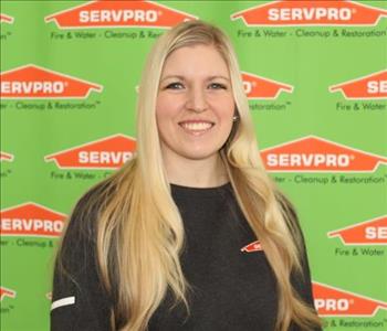 Female SERVPRO employee in front of green backdrop