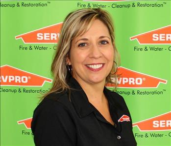 Female SERVPRO employee in front of green backdrop