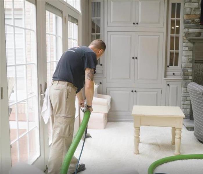 male SERVPRO employee cleaning carpets in residence